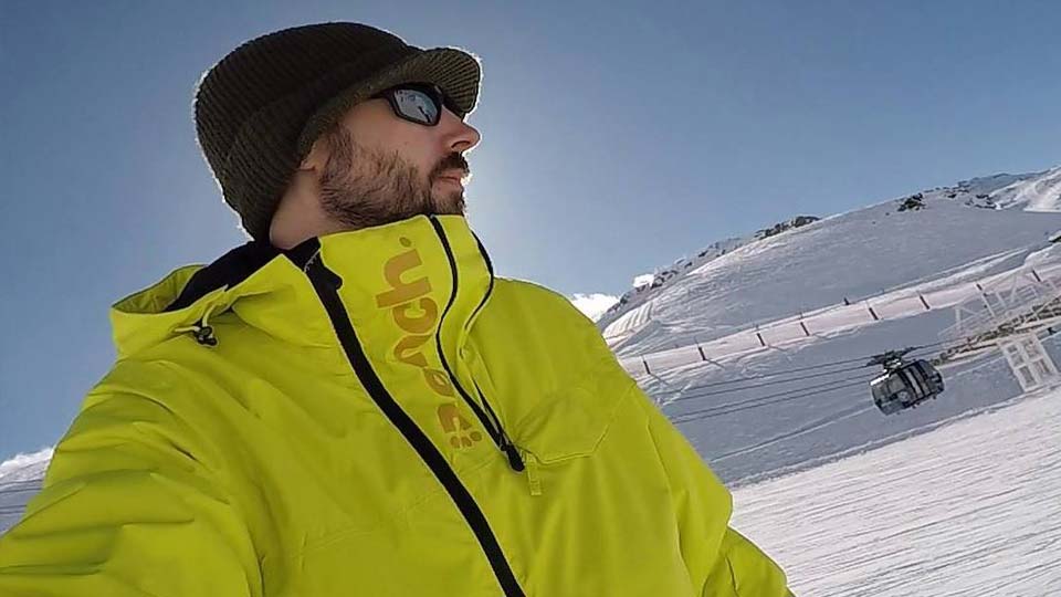 Andrew wearing a ski jacket and snowboarding